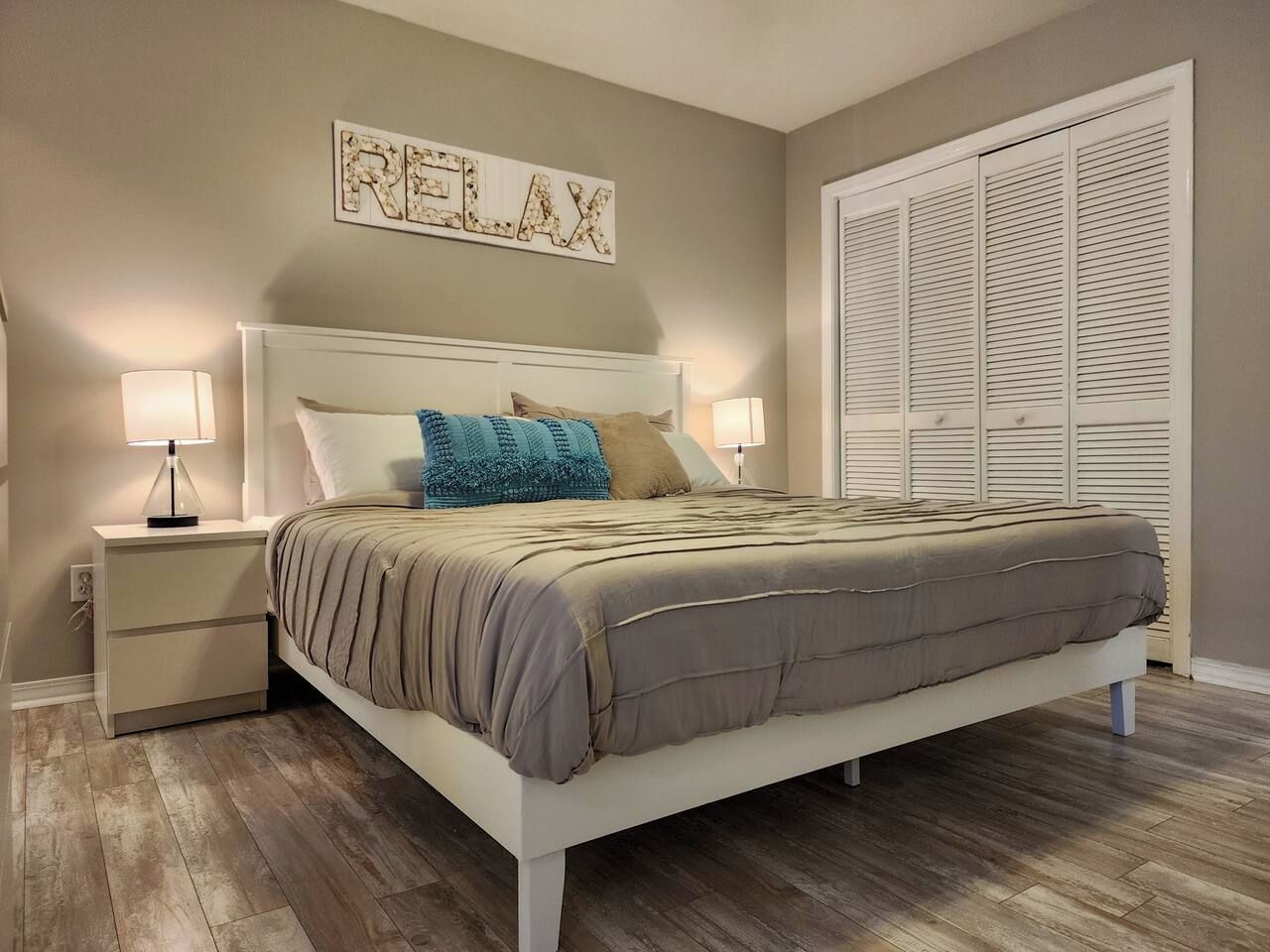 Un dormitorio con cama, mesitas de noche, una obra de arte colgada en la pared y un armario.