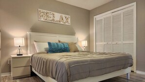 A bedroom with a bed, nightstands, a wall-mounted artwork, and a closet.