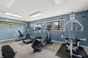 Un gimnasio con cintas de correr, elípticas y equipo de pesas.