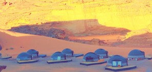 A desert landscape with several dome-shaped tents arranged in rows. - mozoon rum (Wadi Rum)