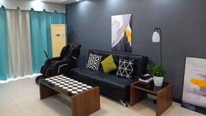 Una sala de estar moderna con sofá, mesa de centro, mesita auxiliar, lámpara y planta en maceta.