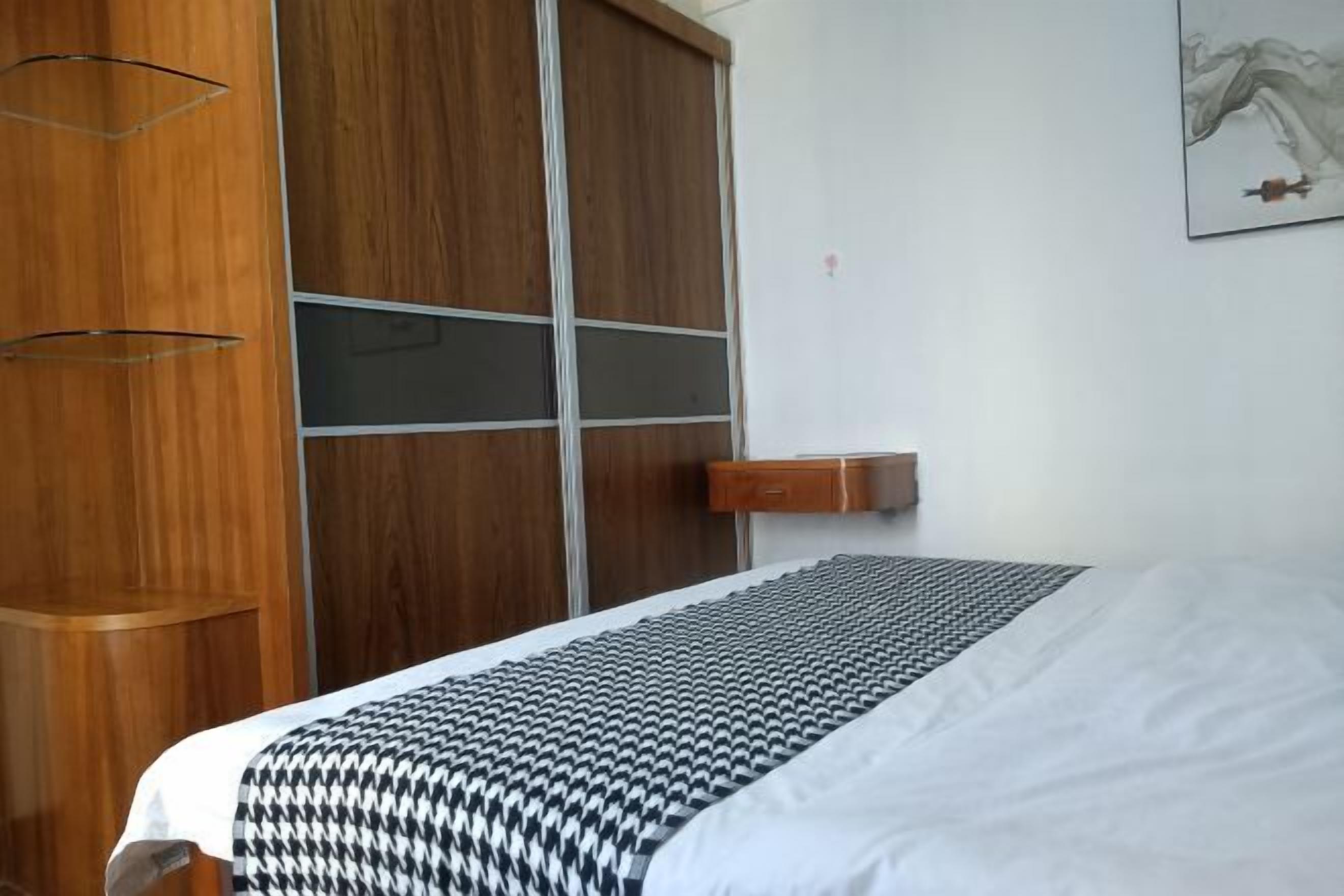 Ein Schlafzimmer mit einem Bett, einem Holzschrank und einem kleinen Nachttisch.