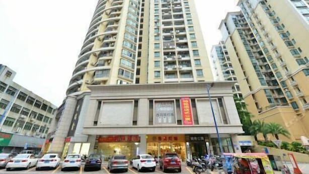 Un edificio residencial de varios pisos con fachada curva, varios balcones y una zona comercial en planta baja con tiendas.