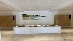 Una habitación amplia con un sofá grande de color blanco, un cuadro de un paisaje costero y armarios de madera.