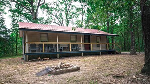 A cabin with a porch, multiple windows, and a fire pit in front.