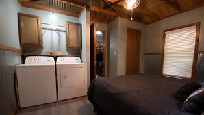 A bedroom with a bed, a washing machine, and a dryer.