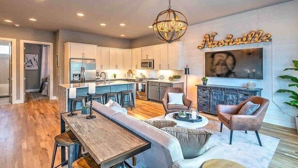 Una cocina moderna con armarios blancos, una isla central y un comedor con un banco y sillas.