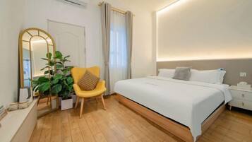 Un dormitorio moderno con una cama grande, una mesita de noche, una silla, un espejo y una planta en maceta.