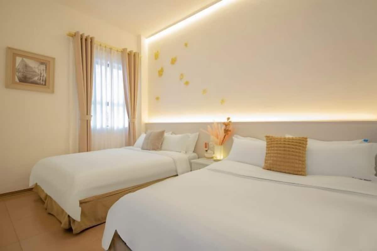 Habitación de hotel con dos camas, una mesita de noche, un cuadro en la pared y una lámpara en el techo.