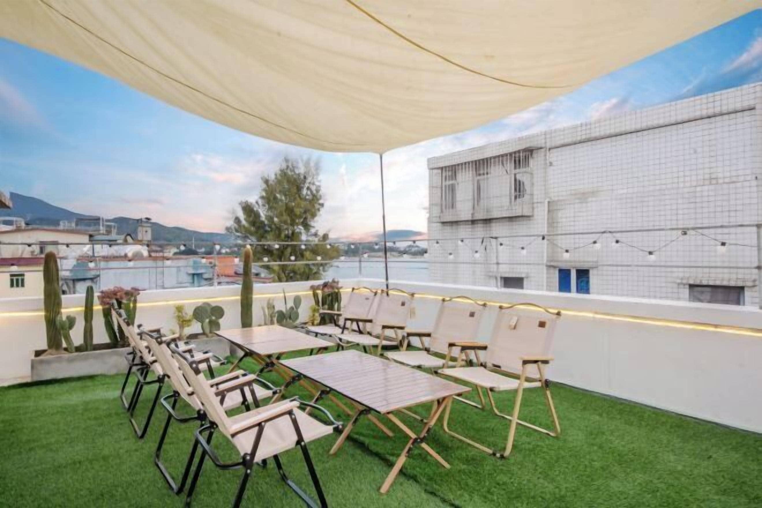 A rooftop terrace with a table and chairs, a canopy, and a view of buildings and mountains.