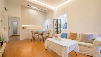Una sala moderna con un sofá, una mesa de comedor y una zona de cocina al fondo.