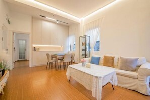 Una sala moderna con un sofá, una mesa de comedor y una zona de cocina al fondo.