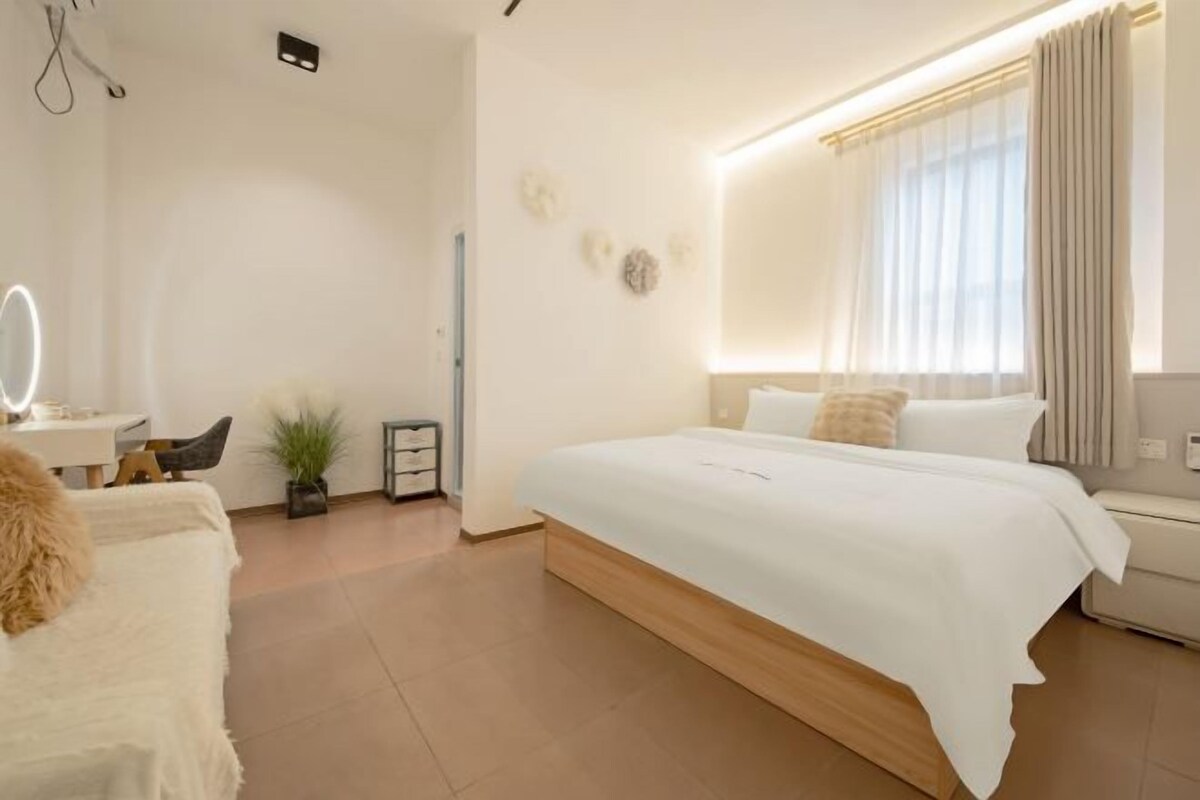 A modern hotel room with a large bed, bedside table, and a mirror.