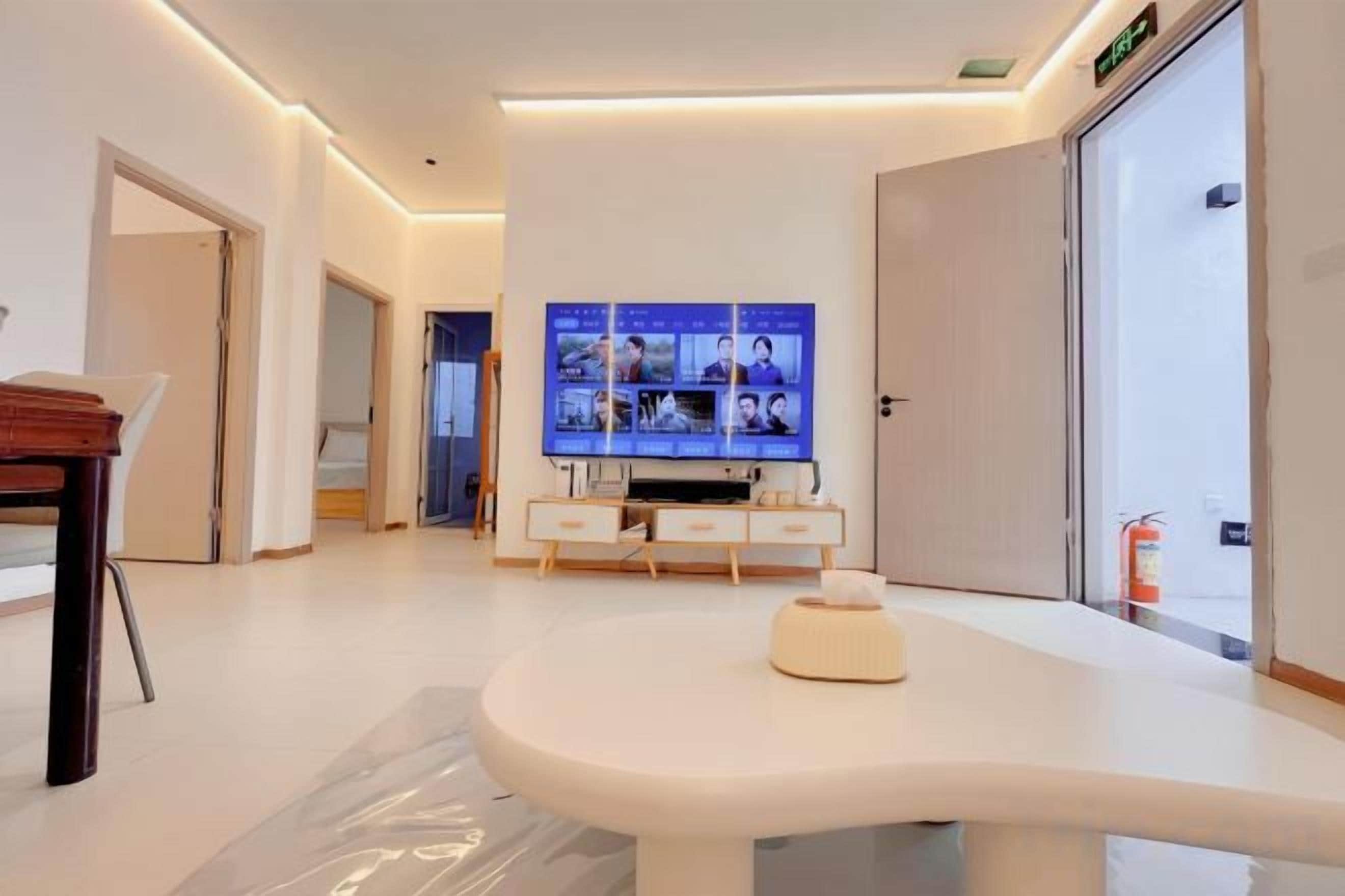 A modern living room with a flat-screen TV mounted on the wall, a round coffee table, and a minimalist design.