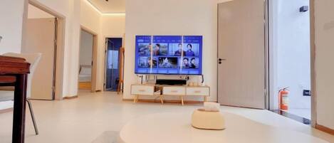 A modern living room with a flat-screen TV mounted on the wall, a round coffee table, and a minimalist design.