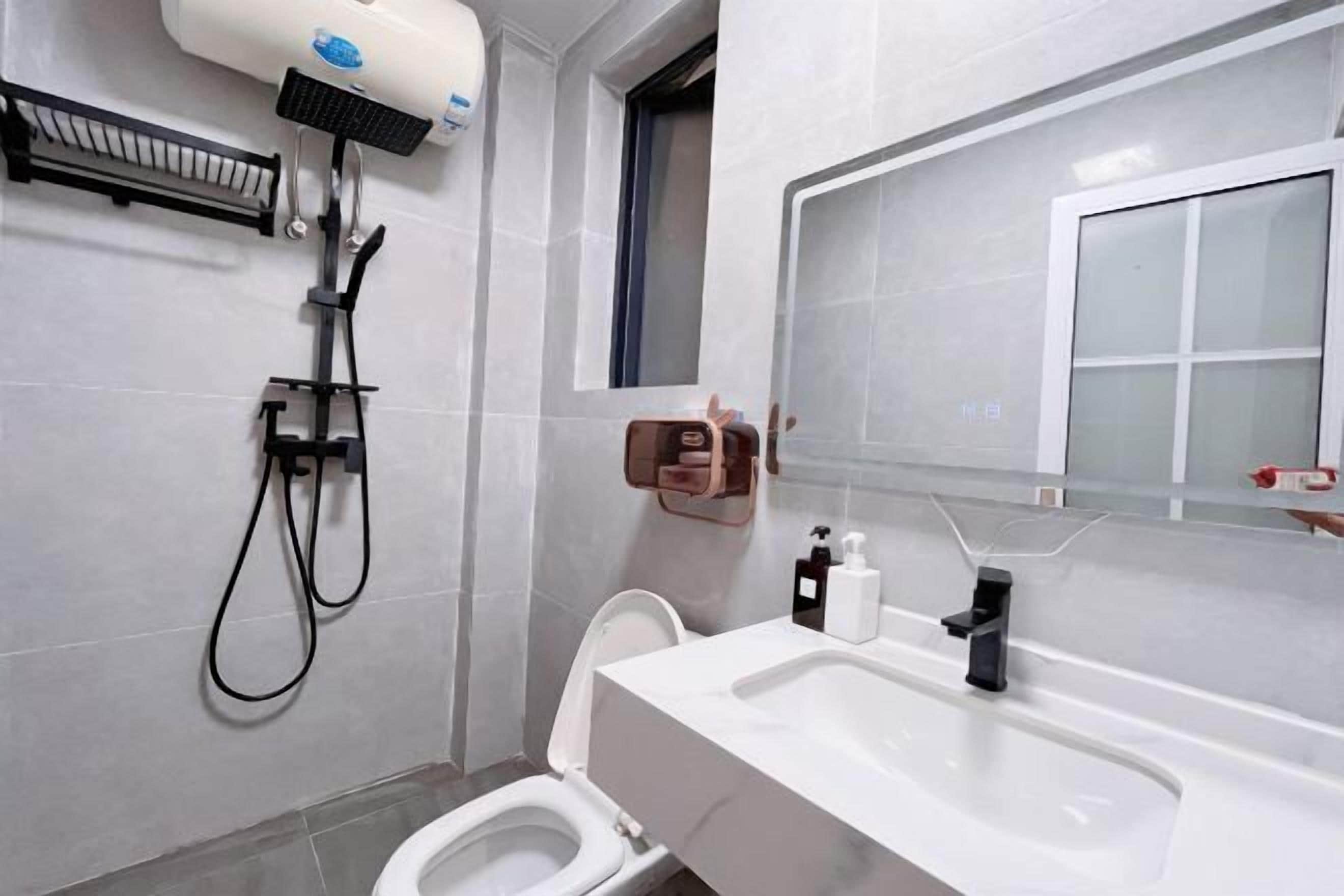 Een moderne badkamer met toilet, wastafel en douche.