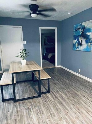 Enjoy a stylish retreat with a large painting and a potted plant, set against a backdrop of a spacious room with a ceiling fan.
