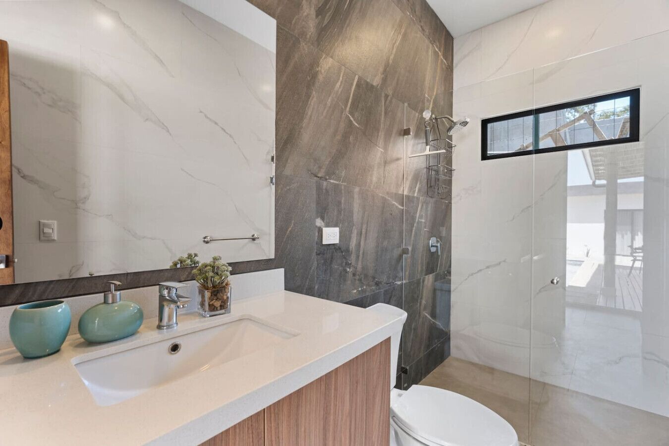 Une salle de bain moderne avec un meuble-lavabo en marbre, un grand miroir et un espace douche.