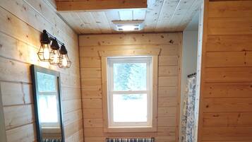 Un baño rústico de cabaña con un lavabo, inodoro y ventana.