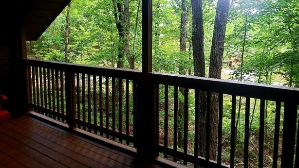 A wooden deck with a railing overlooking a forested area. - Cozy Studio Cabin In The Smokies. Close to Pigeon Forge + Wears Valley. (Sevierville)