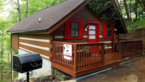 A cabin with a wooden deck, a barbecue grill, and a sign indicating it is a campsite. - Cozy Studio Cabin In The Smokies. Close to Pigeon Forge + Wears Valley. (Sevierville)