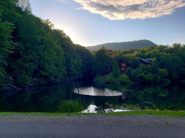 A lodge surrounded by dense forest and a lake, with a mountain in the background.