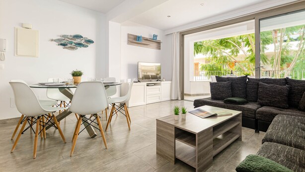 A modern living room with a dining area, a sofa, and a TV. - YourHouse Can Cortana (Pollensa)