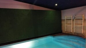 Une piscine à bord incurvé, un mur vert foncé et un plafond orné d’un motif étoilé.