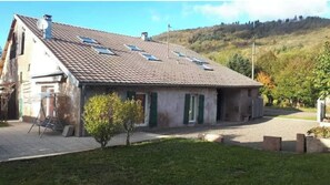 A two-story house with a sloped roof, solar panels, and a small front yard.