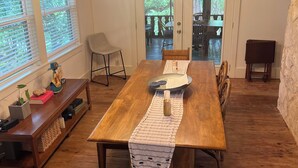 A dining area with a wooden table, benches, and a chandelier. - Completely renovated 1930s Cottage on the Guadalupe River. Ideal location! (New Braunfels)