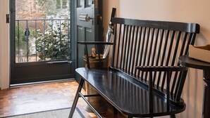 A modern interior with a black bench, a decorative mirror, and a door leading to an outdoor area. - GreenLeaf | Close to UVA and Downtown, Sleeps 7 with Yard! (Charlottesville)