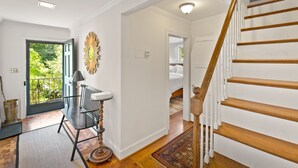 A staircase with wooden steps and white railings, leading to a bedroom with a large window and a view of greenery outside. - GreenLeaf | Close to UVA and Downtown, Sleeps 7 with Yard! (Charlottesville)