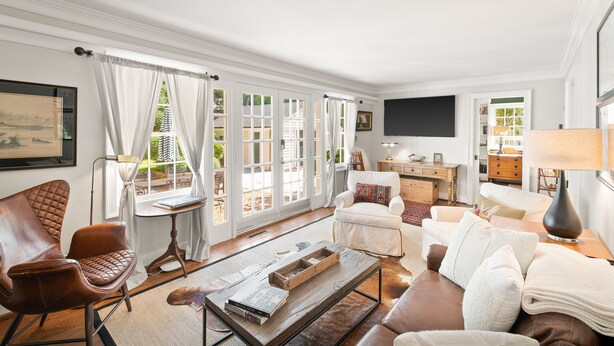 A spacious living room with a brown leather armchair, a white sofa, and a coffee table. - GreenLeaf | Close to UVA and Downtown, Sleeps 7 with Yard! (Charlottesville)