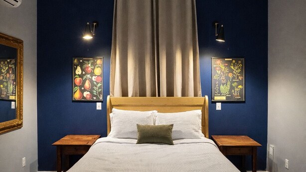 Ein Schlafzimmer mit einem Holzbett, zwei Nachttischen, einem Kopfteil und zwei Wandleuchten.