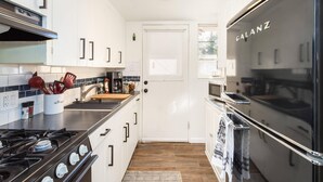 A modern kitchen with white cabinets, a stainless steel stove, and a black refrigerator. - The Teal Door | UofA Central Newly Renovated 1BR (Tucson)