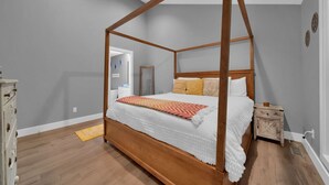 Un lit à baldaquin à quatre poteaux, avec une structure en bois, du linge de lit blanc et des coussins décoratifs.