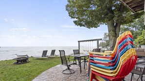 A patio with a table and chairs, a fire pit, and a stack of colorful chairs.