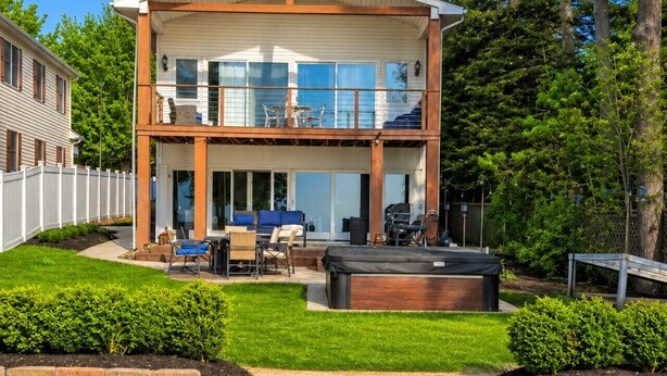 A two-story house with a patio, outdoor seating, and a barbecue area. - Libby`s Cove - Swim spa open all year! kayaks&more (Port Sanilac)