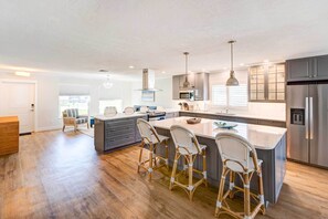 A modern kitchen with a central island, bar stools, and stainless steel appliances. - Naples Vacation Home: Private Pool + Hot Tub! (Naples)