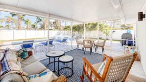 A covered outdoor seating area with a pool, lounge chairs, and a table. - Naples Vacation Home: Private Pool + Hot Tub! (Naples)