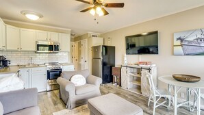 A modern kitchen with white cabinets, stainless steel appliances, and a dining area with a round table and wicker chairs. - On-Site Beach Access: Apt in Hilton Head Island! (Hilton Head Island)