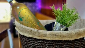 Una botella de vino en una cesta tejida con una pequeña planta.