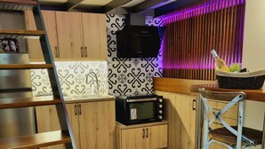 Cocina compacta con armarios de madera, microondas y tostadora.