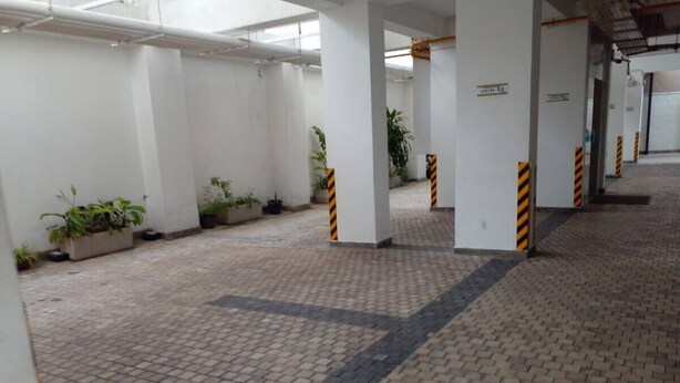 A spacious indoor area with tiled flooring, white walls, and several potted plants. - Luxury Apartment in Colombo 7 (Colombo)