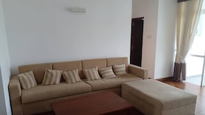 A living room with a beige sectional sofa, a wooden coffee table, and a small ottoman. - Luxury Apartment in Colombo 7 (Colombo)