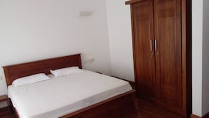 A bedroom with a wooden bed and a wardrobe. - Luxury Apartment in Colombo 7 (Colombo)