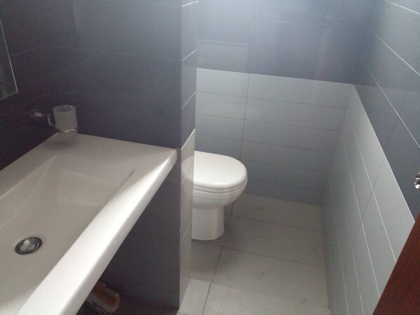 A bathroom with a bathtub, toilet, and tiled walls.