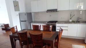 A modern kitchen with white cabinets, a gas stove, and a refrigerator. - Luxury Apartment in Colombo 7 (Colombo)