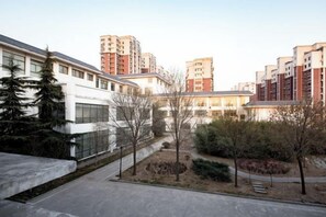 A courtyard with modern buildings, a pathway, and a small garden area. - Yu Jing Lou Hotel (Ci County)