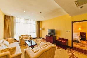 A hotel room with a sofa set, a coffee table, a TV, a bed, and a large window with curtains. - Yu Jing Lou Hotel (Ci County)